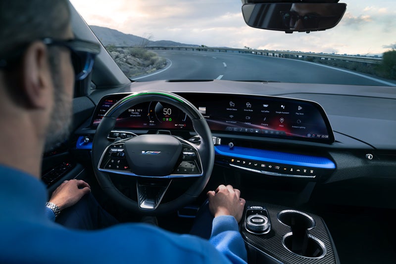 Front View of the 2026 OPTIQ-V Driving Through the Dusk Utilizing its Headlights | Cadillac of New Orleans in Metairie LA