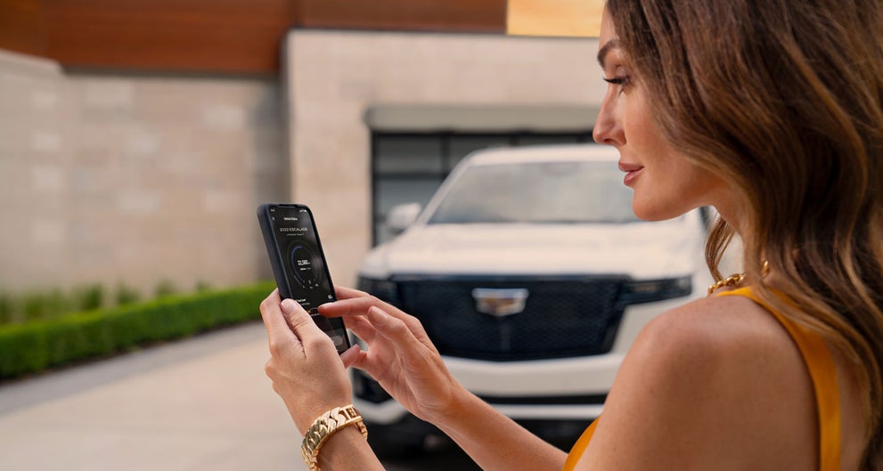 lady checking her mobile with a Cadillac vehicle background | Cadillac of New Orleans in Metairie LA